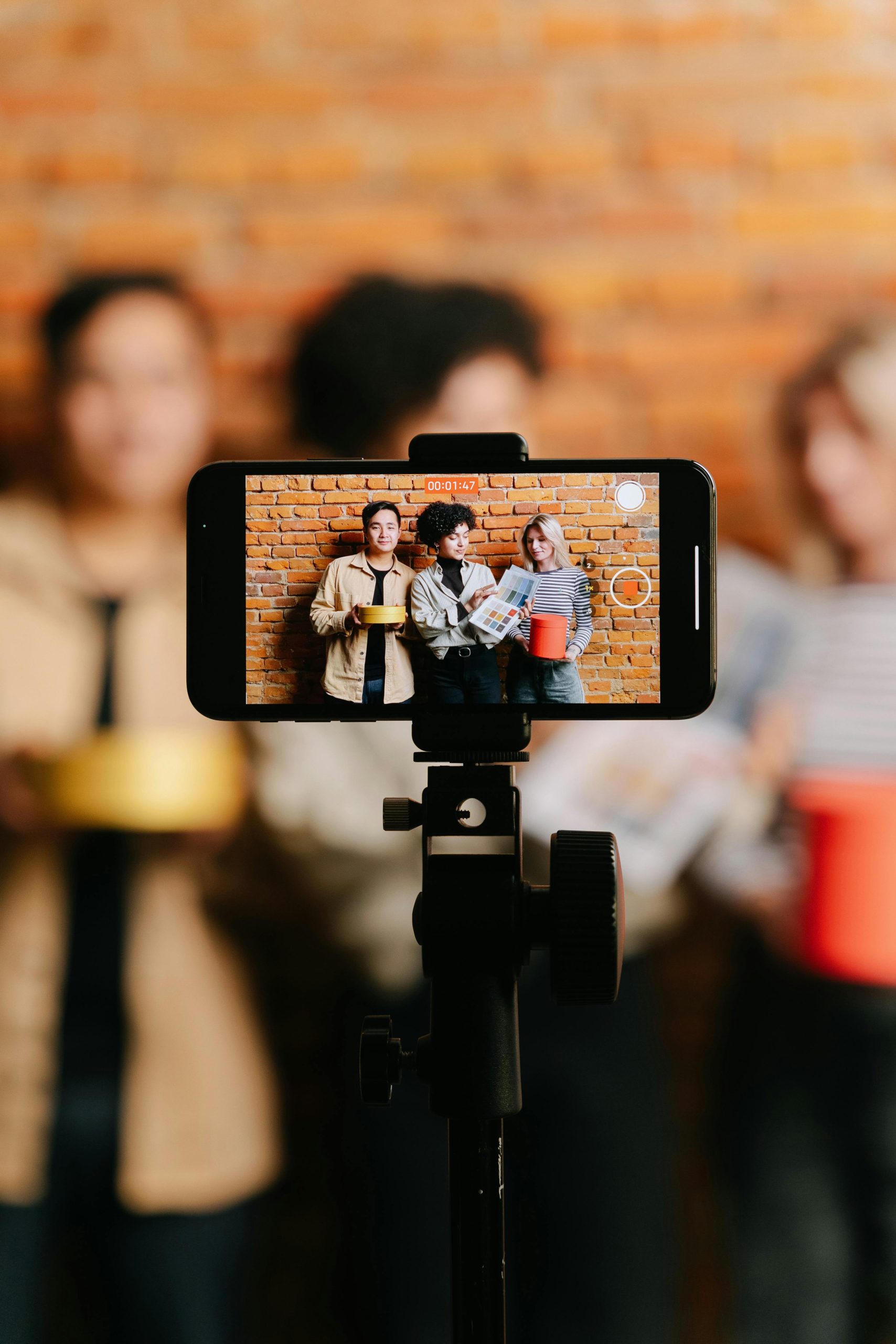 Diverse group of friends filming a video with a smartphone on a tripod indoors.